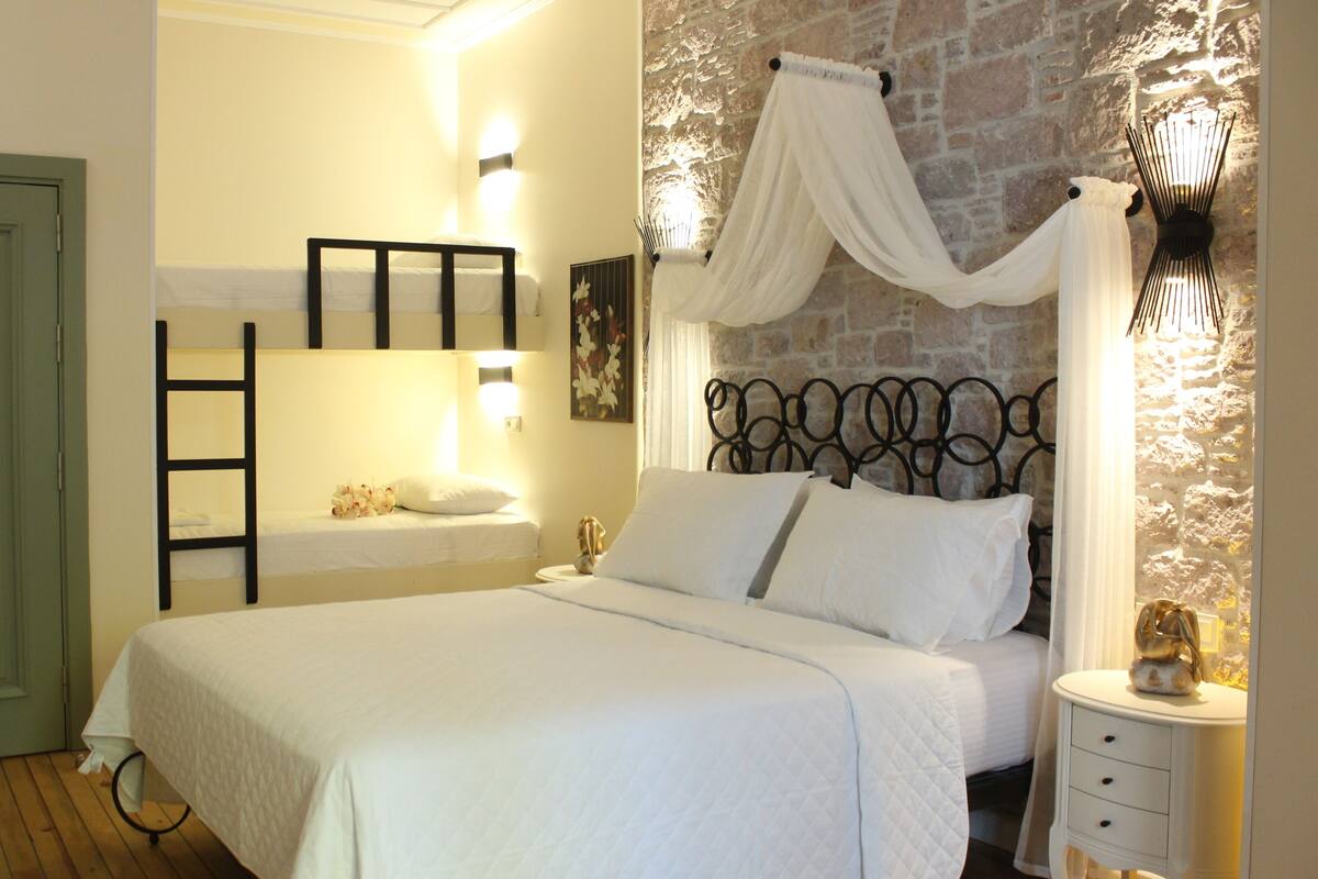 A bedroom with a bunk bed, a bedside table with a lamp, and a decorative wall.