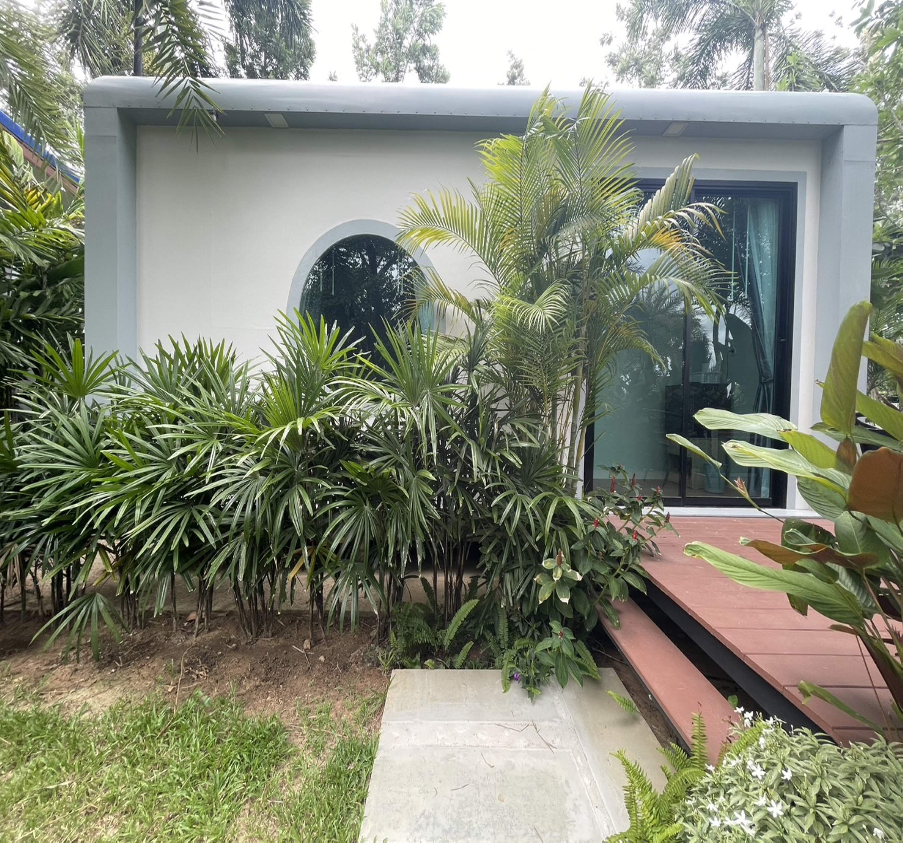 Un bâtiment moderne doté d’une grande baie vitrée et d’un chemin en béton menant à l’entrée.