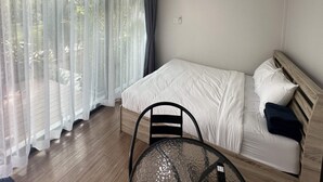 A bedroom with a bed, a chair, and a table. - BannRai Tayai Cafe and Resort (Pattaya)