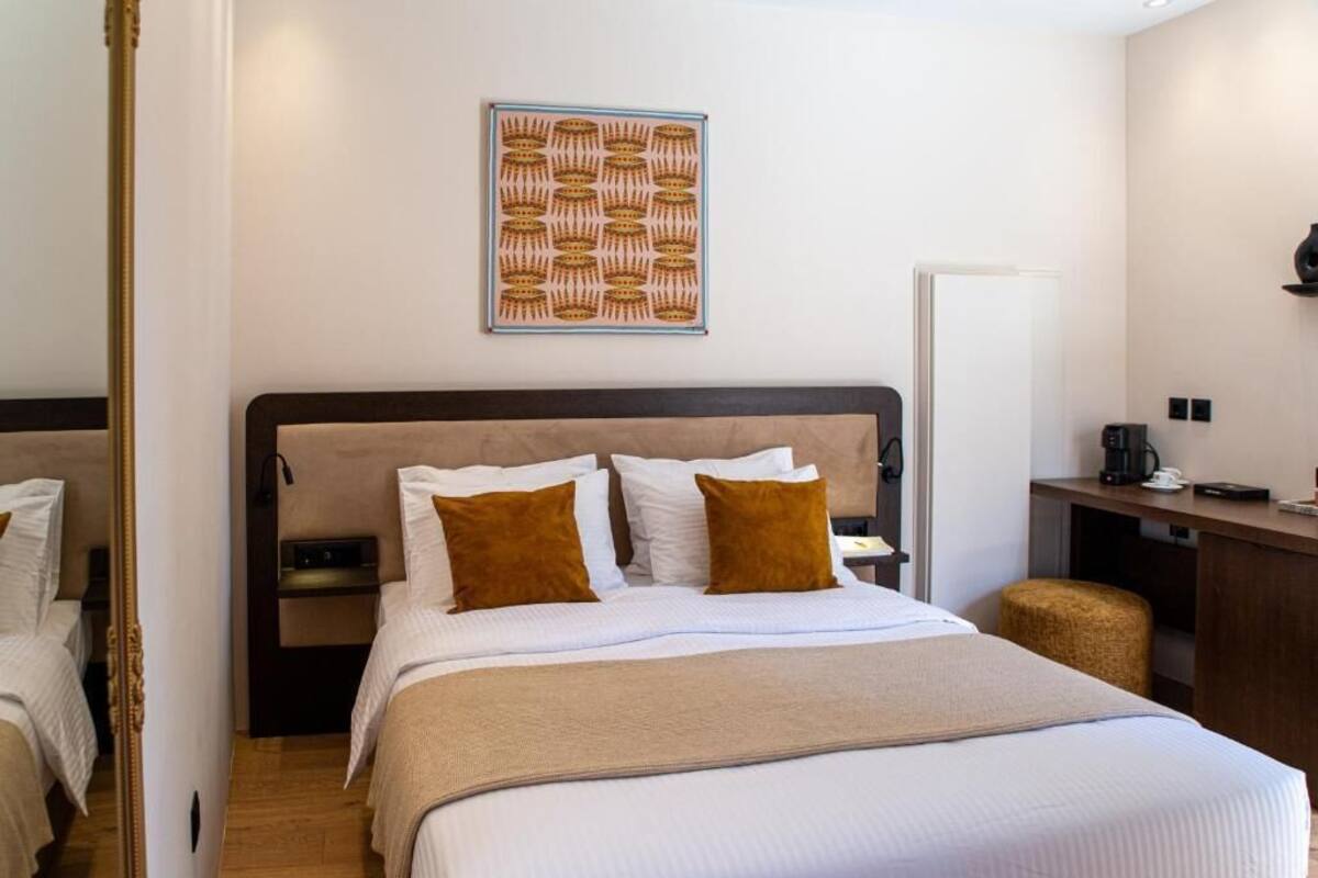 A hotel room with a large bed, two bedside tables, a small desk, and a coffee machine.