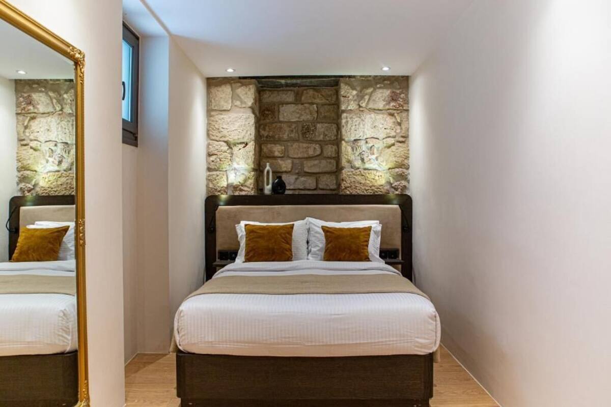 A bedroom with a stone wall, a bed with white bedding, and a large mirror.