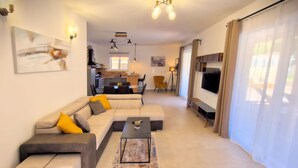 A modern living room with a sectional sofa, a coffee table, and a TV. There is a kitchen in the background with a dining area. - A picturesque holiday home, located in a quiet part of the Rovinj municipality (Rovinjsko Selo)