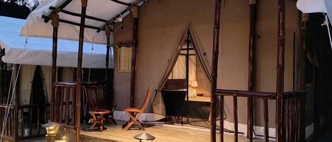 A tented accommodation with a covered porch, stone steps, and outdoor lighting.