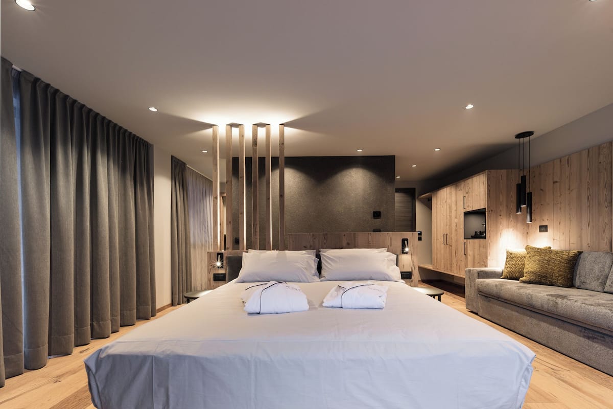 A modern bedroom with a large bed, wooden flooring, and a built-in wardrobe.