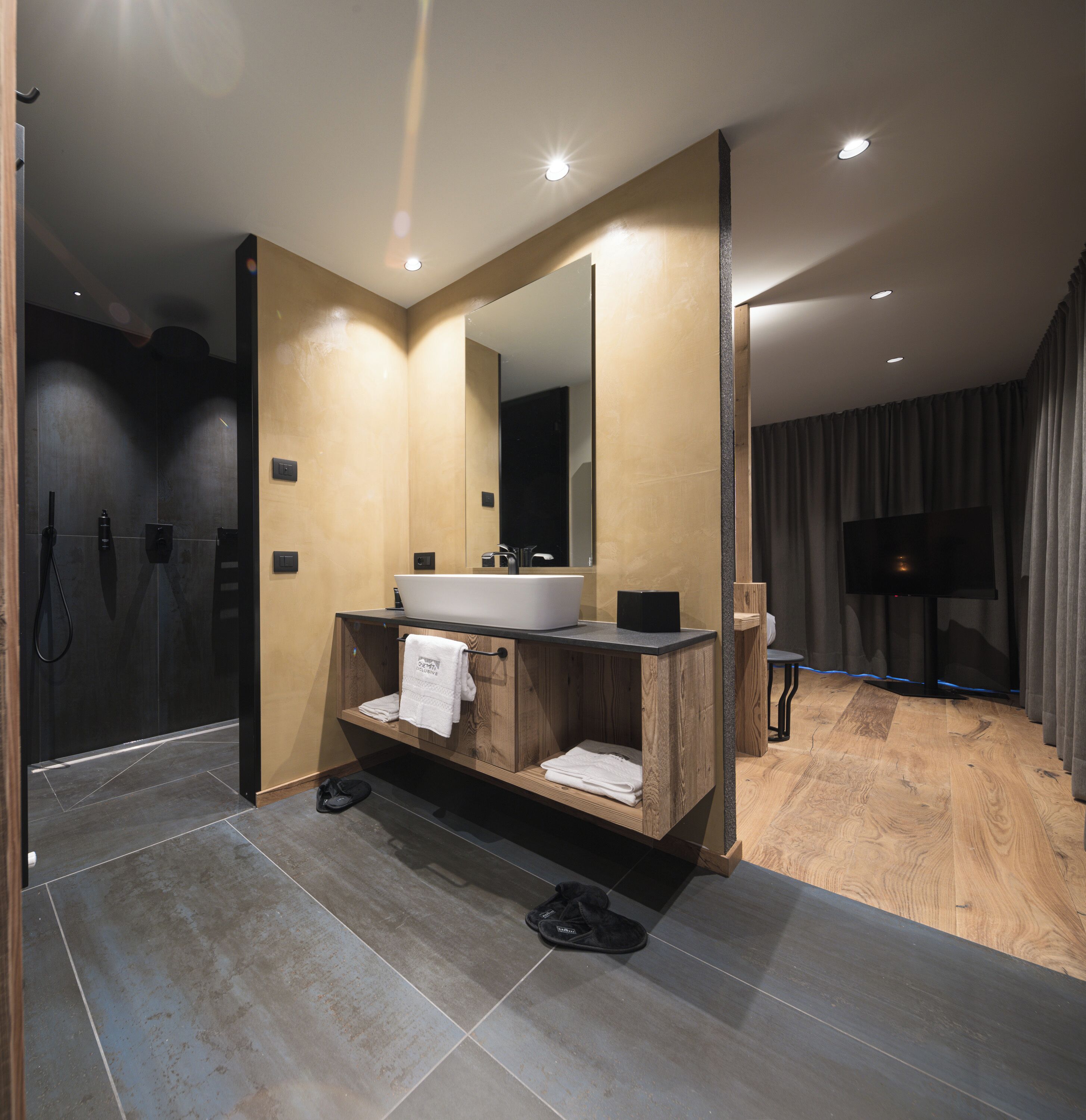 Un baño moderno con un espejo grande, tocador de madera y una bañera.