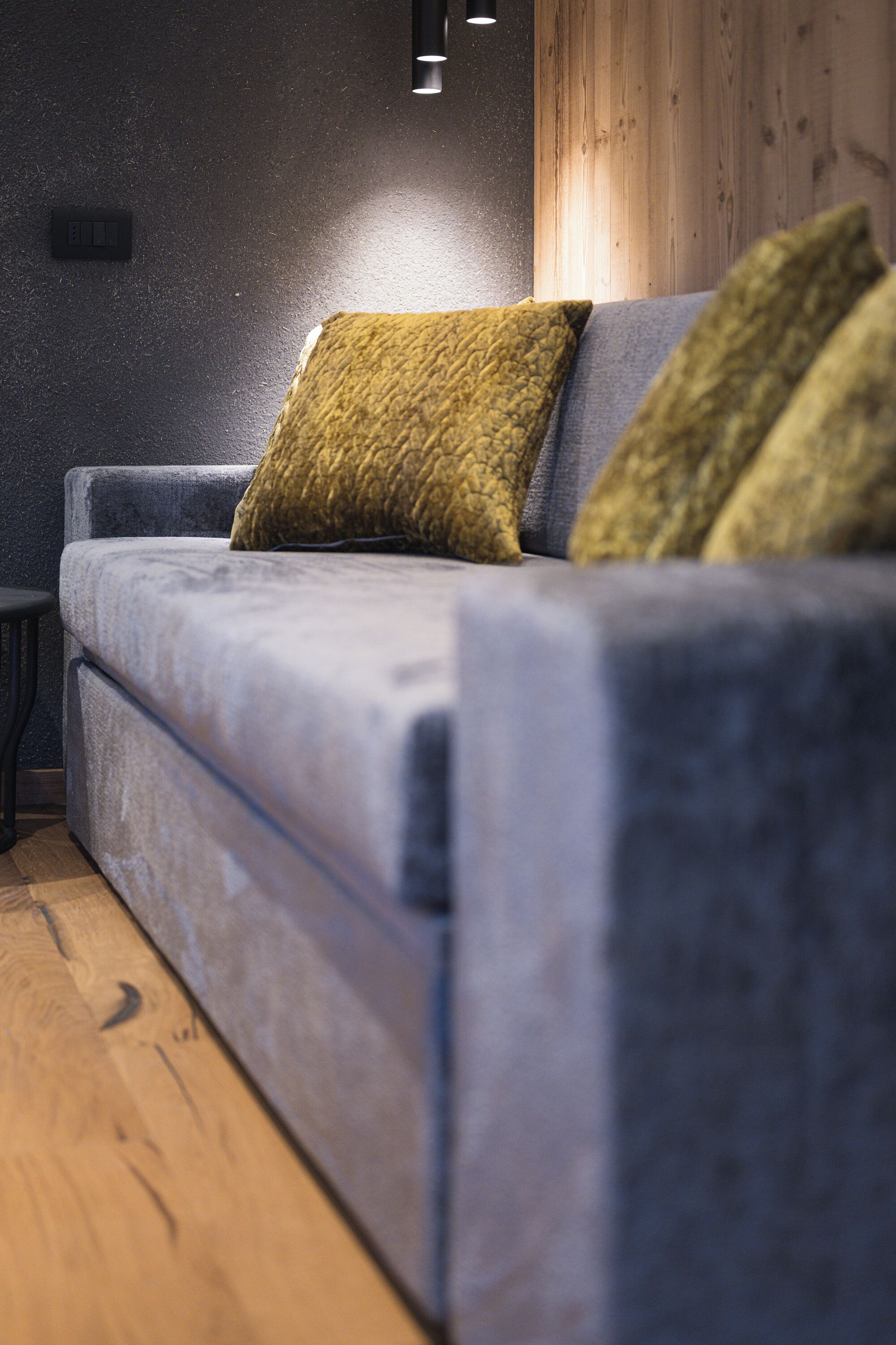 A modern living room with a grey sofa, two green cushions, and a wooden floor.