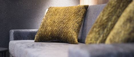 A modern living room with a grey sofa, two green cushions, and a wooden floor.