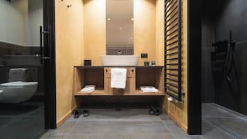 A modern bathroom with a large mirror, a sink, and a toilet.