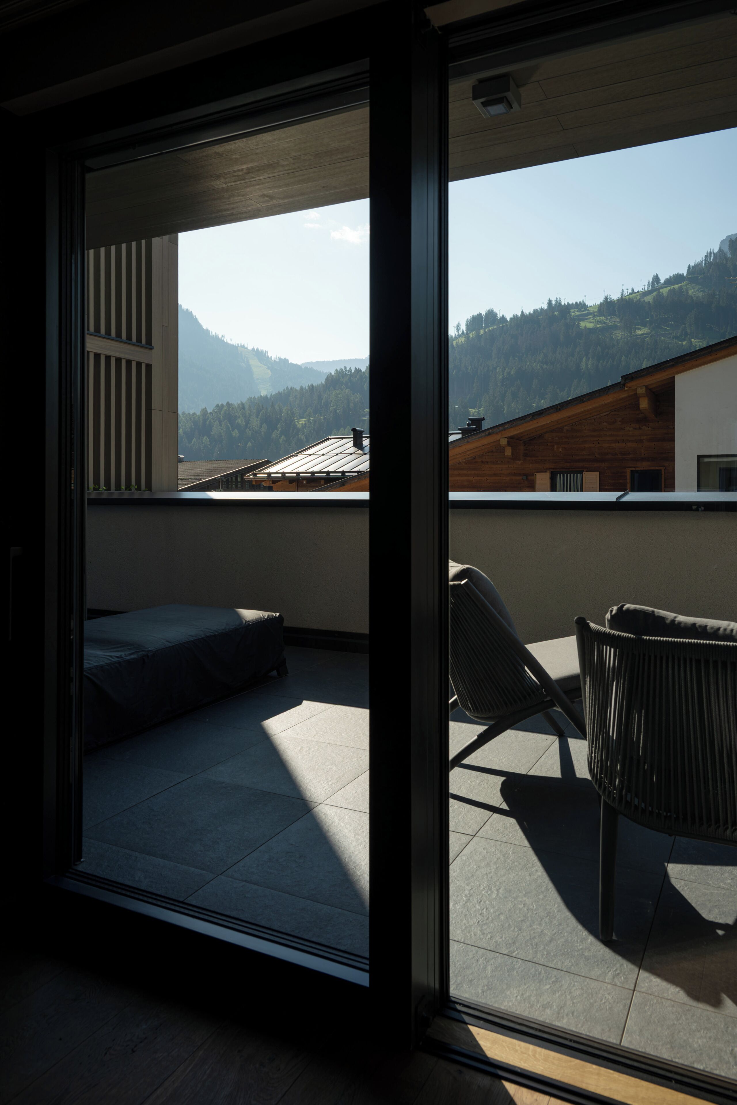 A balcony with a bed, a chair, and a view of mountains.