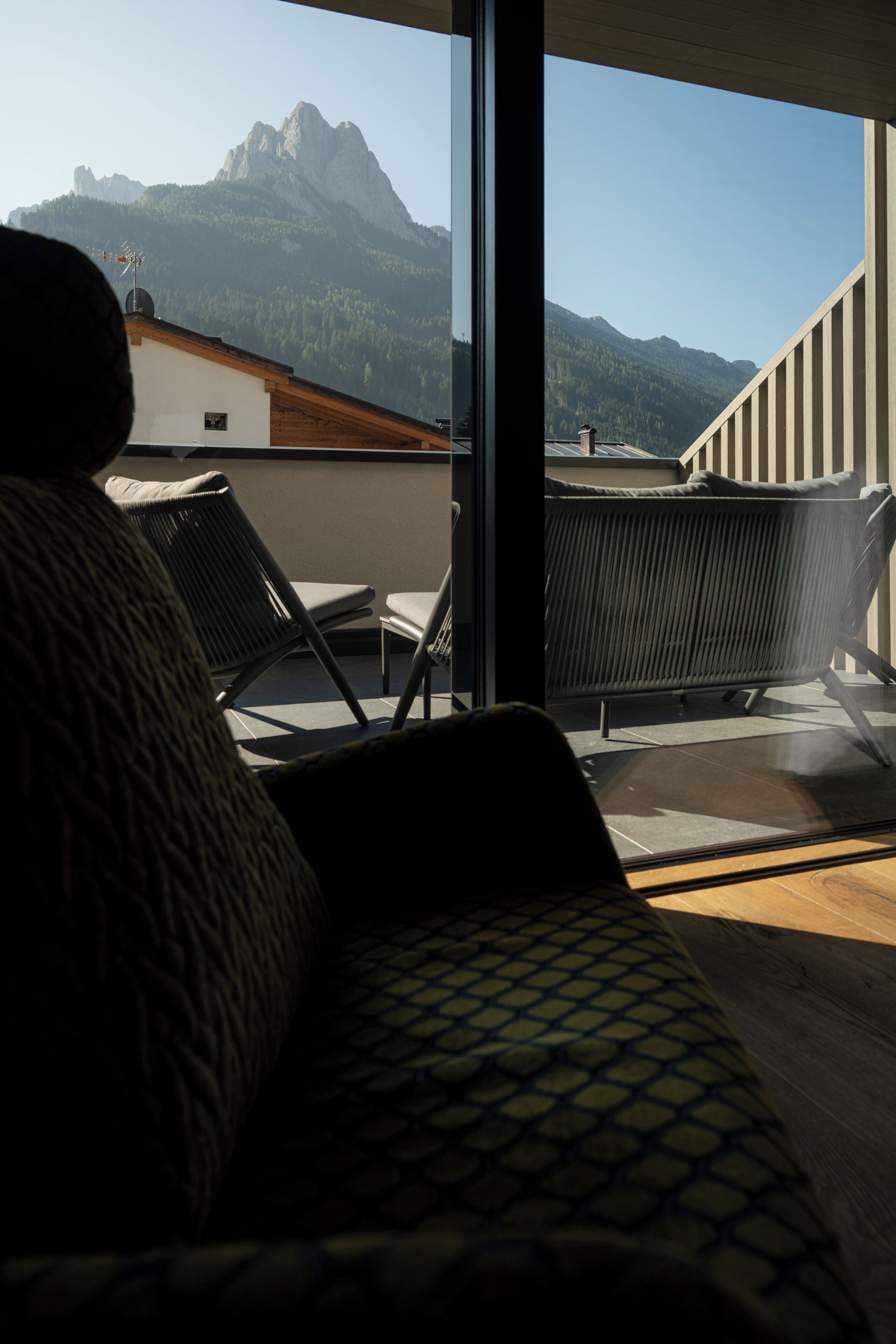 Un balcon avec vue sur les montagnes, une chaise et un canapé.