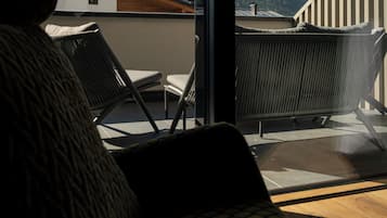 Un balcon avec vue sur les montagnes, une chaise et un canapé.