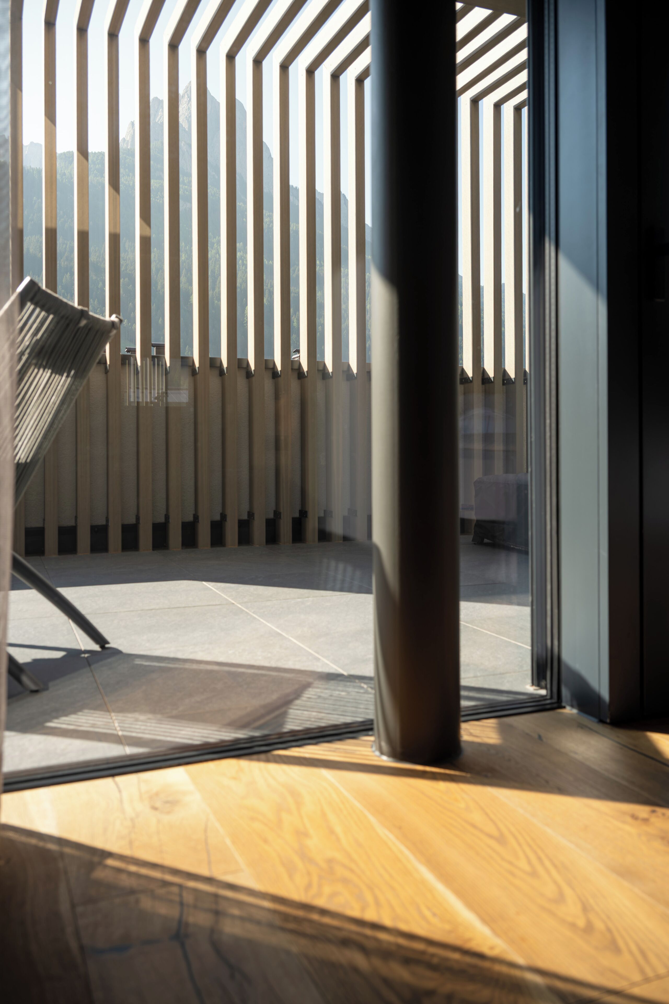 Un intérieur moderne avec un plancher en bois, un banc en métal et un mur orné de motifs.