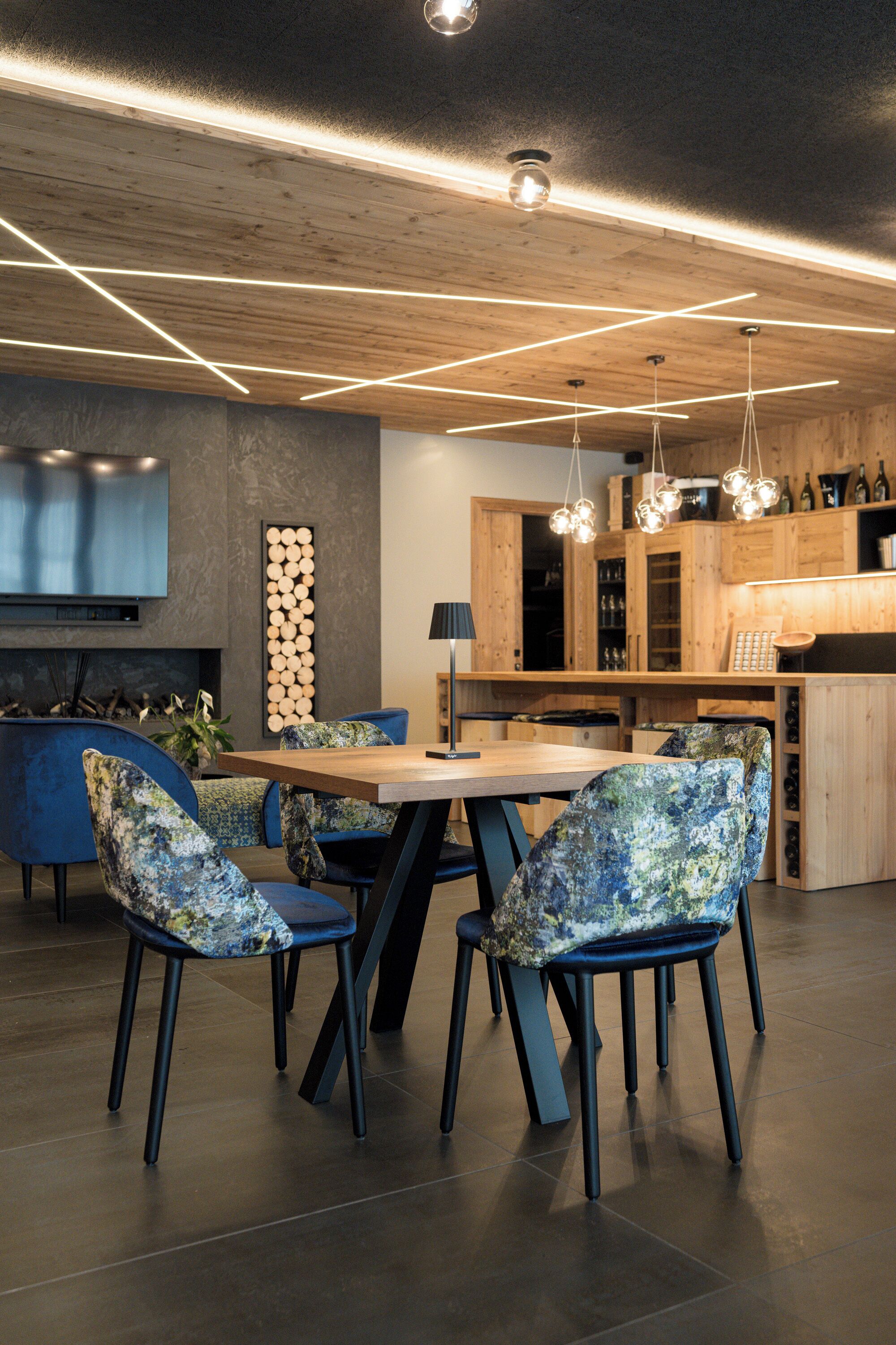 A modern kitchen with wooden cabinets, a built-in stove, and a dining area with a wooden table and patterned chairs.