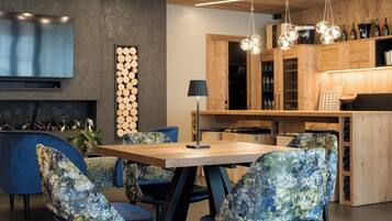 A modern kitchen with wooden cabinets, a built-in stove, and a dining area with a wooden table and patterned chairs.
