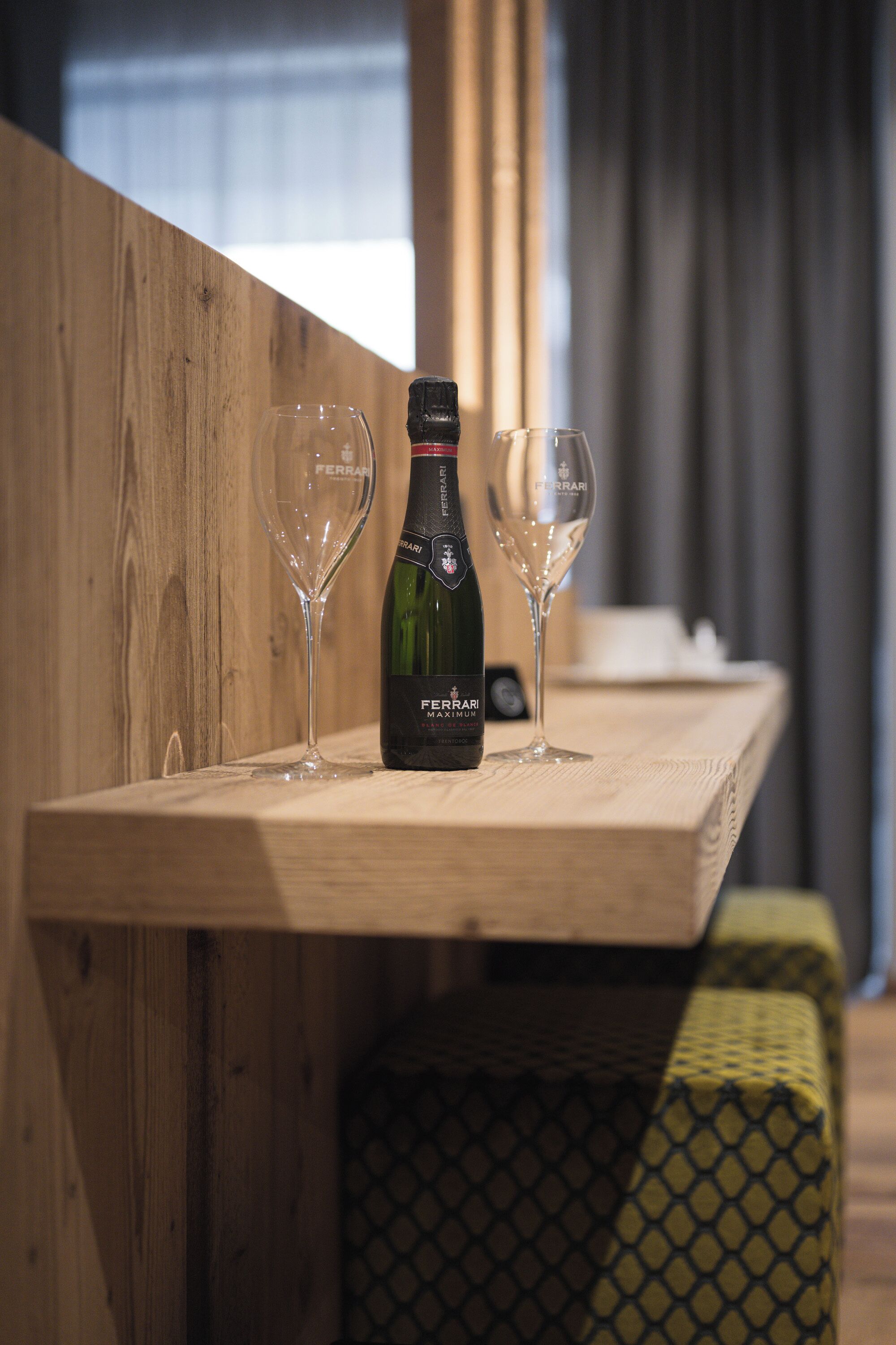 A wooden table with a bottle of wine and two glasses on it.