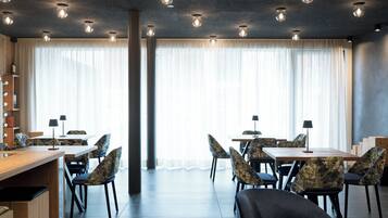 A modern dining area with a long wooden table, multiple chairs, and pendant lighting.