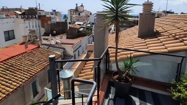 A rooftop terrace with potted plants, a metal railing, and multiple antennas. - APARTAMENTOS APARTACO (Sitges)