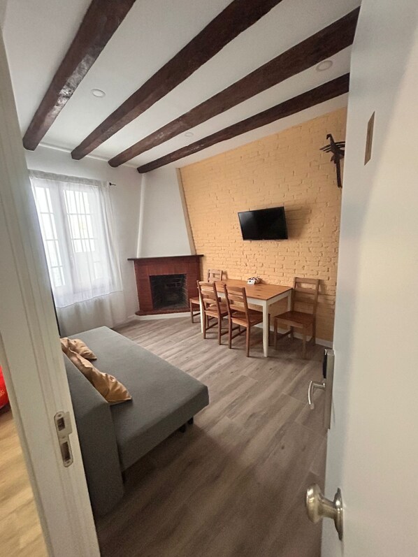 A cozy living room with a fireplace, a dining area, and a sofa. - APARTAMENTOS APARTACO (Sitges)