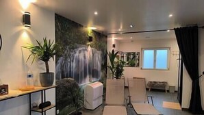Una sala de estar moderna con un mural de una cascada, un sofá, dos sillones y una mesa de centro.
