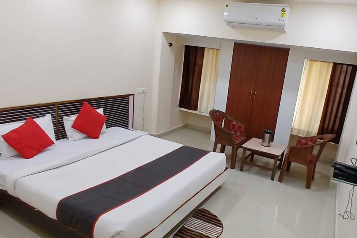 A hotel room with a bed, a desk, a chair, a TV, and a wardrobe.