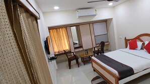 A hotel room with a bed, a desk, a chair, and a wardrobe. - Hotel Sharda By Edge By GRB (Raipur)