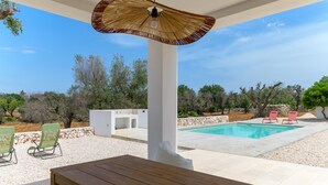 Un espace extérieur abrité comprenant une piscine, des chaises longues et une table en bois.