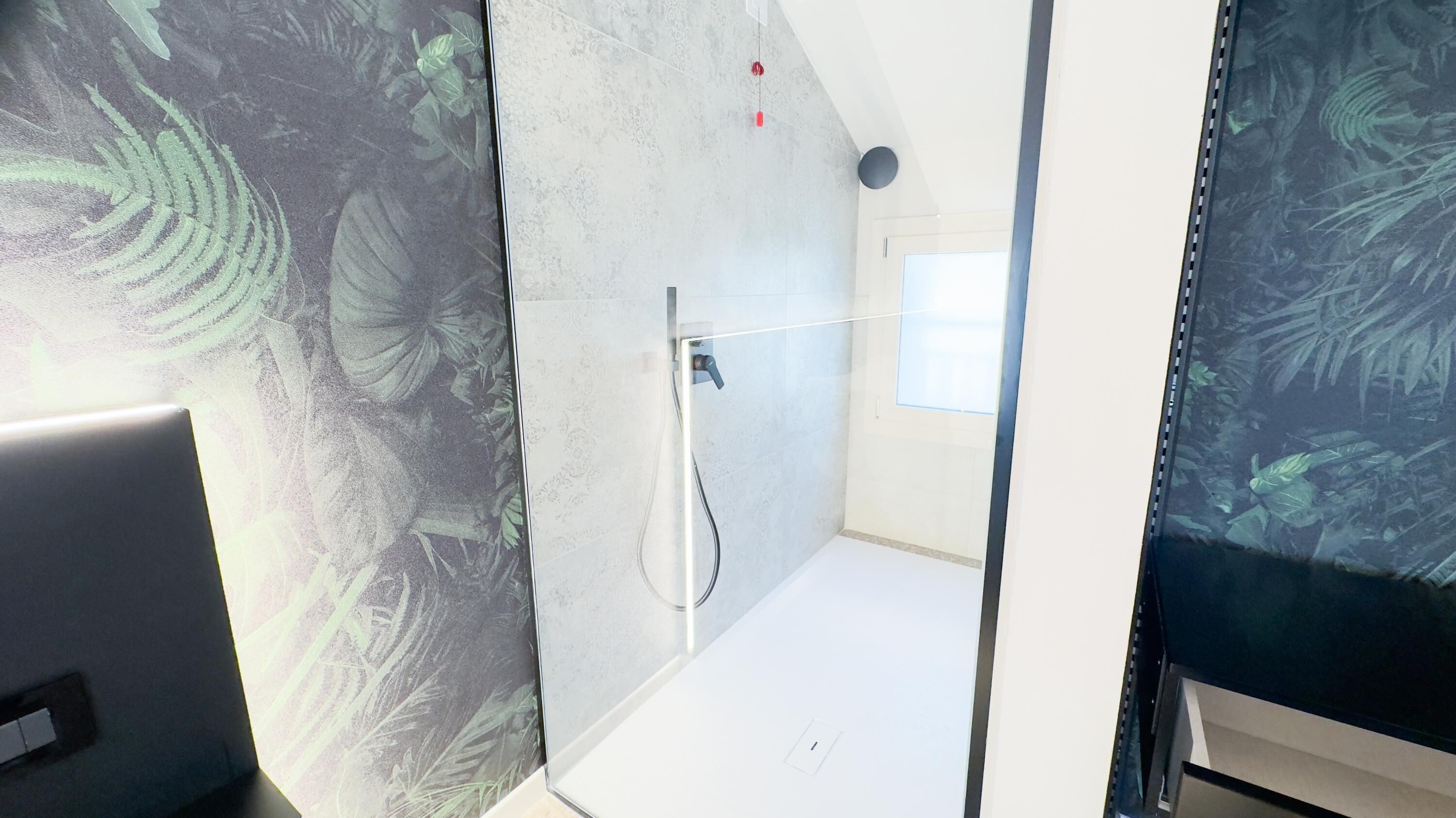 Un bagno moderno con doccia, pannello comandi a vista e finestra che lascia entrare luce naturale.