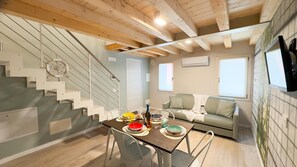 A cozy living area with a staircase, a dining table set with plates and glasses, a sofa, and a TV mounted on the wall. - Graceful Apartments Paradise by Ca-sa Check (Chioggia)