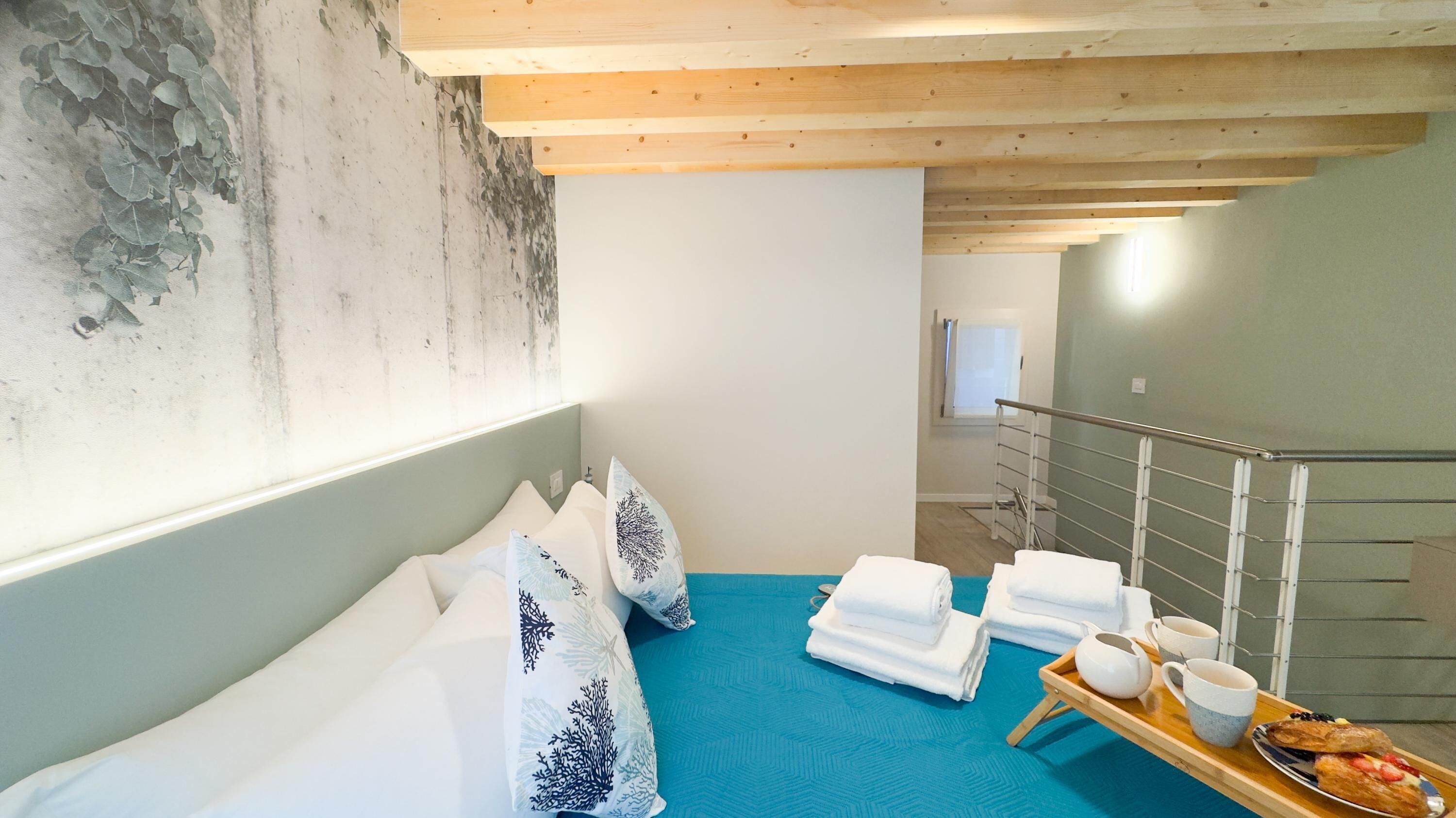 A hotel room with a bed, towels, a tray with breakfast items, and a view of the hallway.