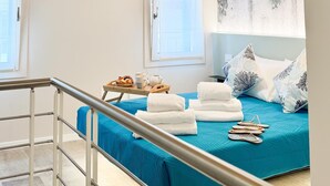 Una habitación con techo de madera, una cama con colcha azul, toallas blancas y una pequeña mesa con una bandeja de comida.