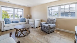 A living room with a sofa, armchair, and round coffee table. - Spacious 3BR Condo Near Ventnor Beach (Ventnor City)