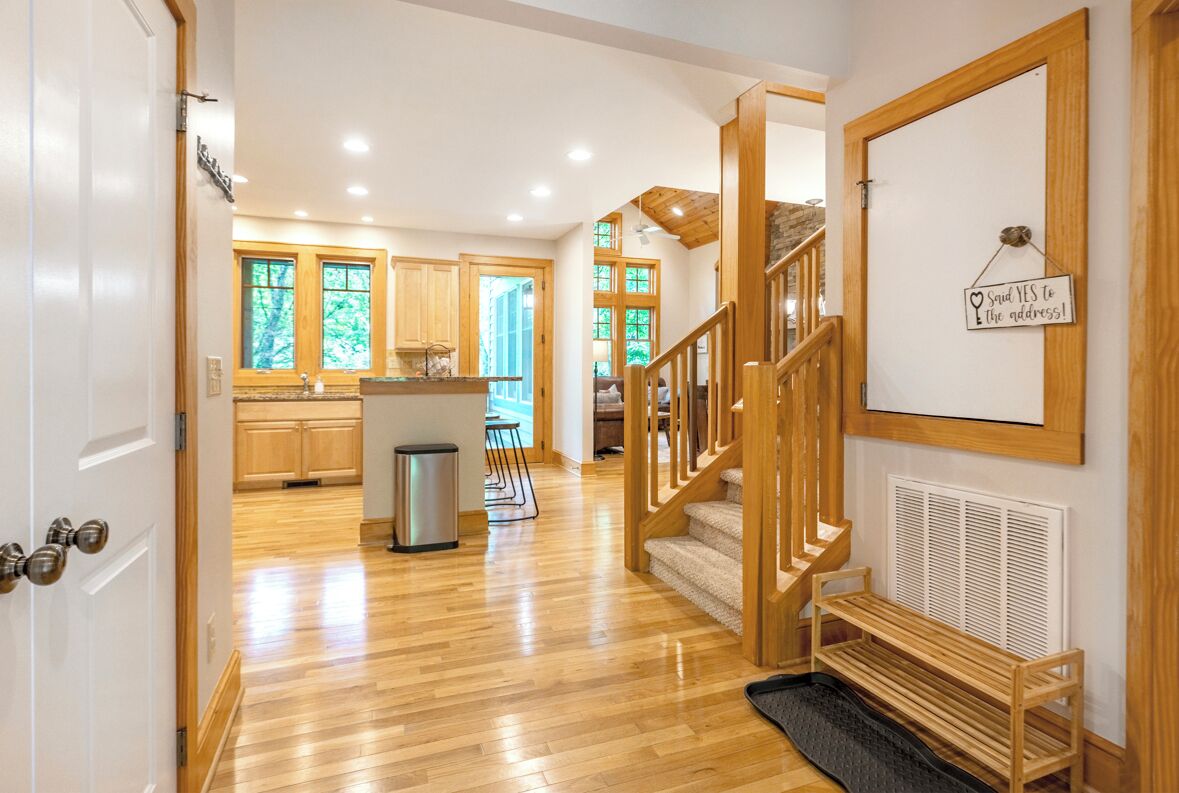A spacious kitchen with wooden cabinets, a central island, and a staircase leading to an upper level.