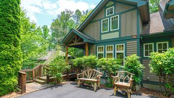 A two-story house with a porch, wooden benches, and a staircase leading to the entrance.