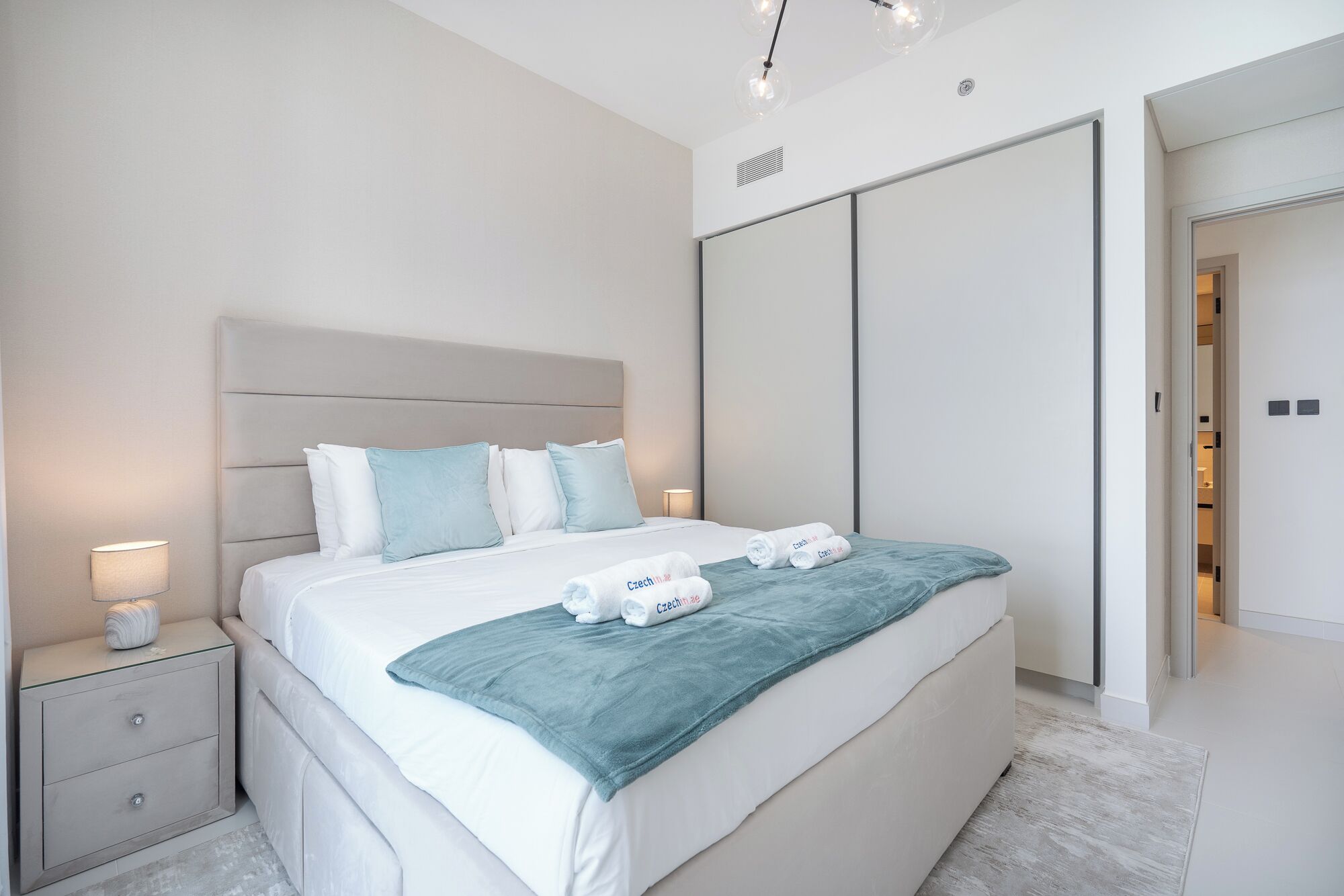 Ein modernes Schlafzimmer mit einem großen Bett, einem Nachttisch, einem Kleiderschrank und einem durch eine offene Tür einsehbarer Badezimmer.