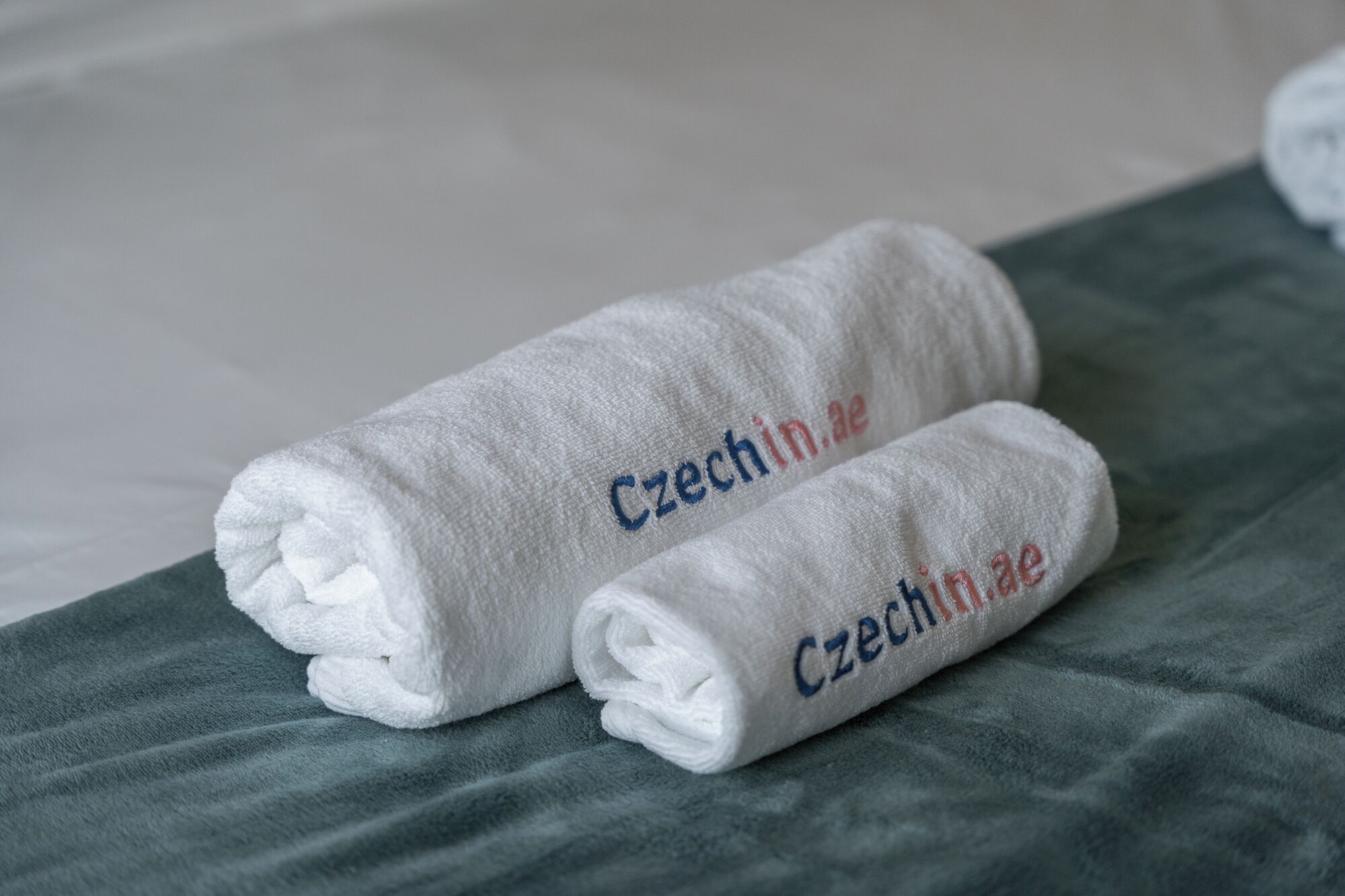 Dos toallas blancas dobladas con el bordado 'Czechia', sobre una superficie verde con textura.