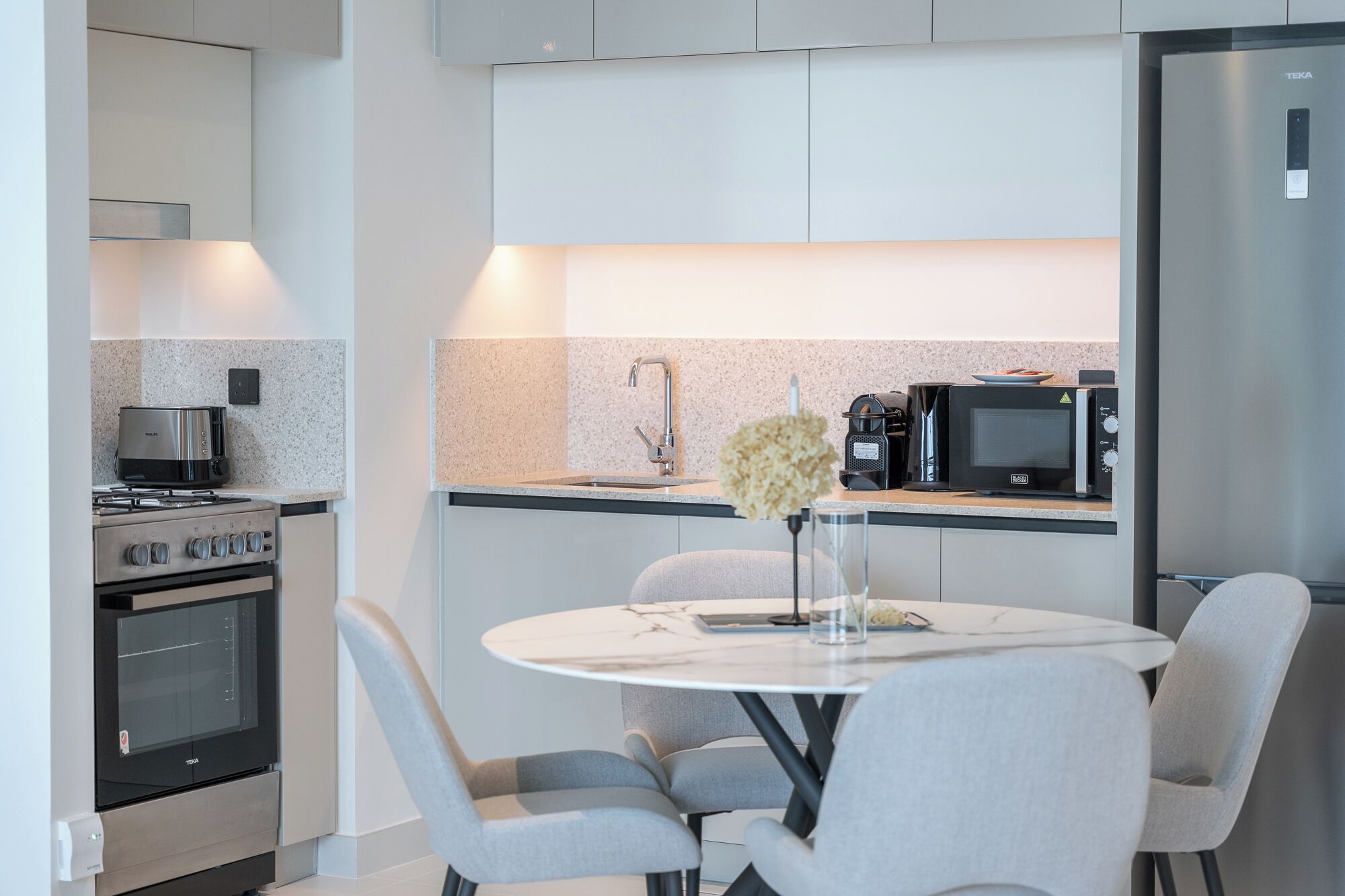 A modern kitchen with a dining area, featuring a stove, microwave, and sink.