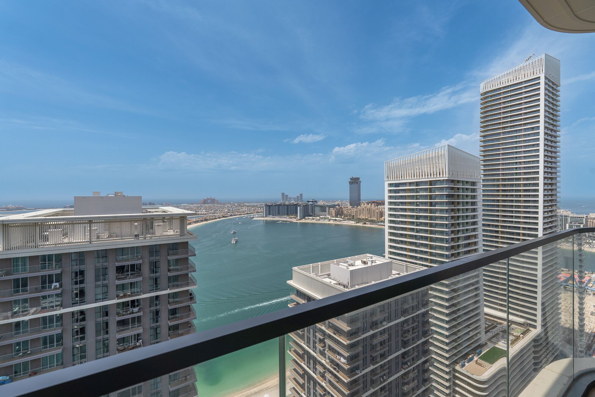A high-rise building with a view of a marina and a clear blue sky.