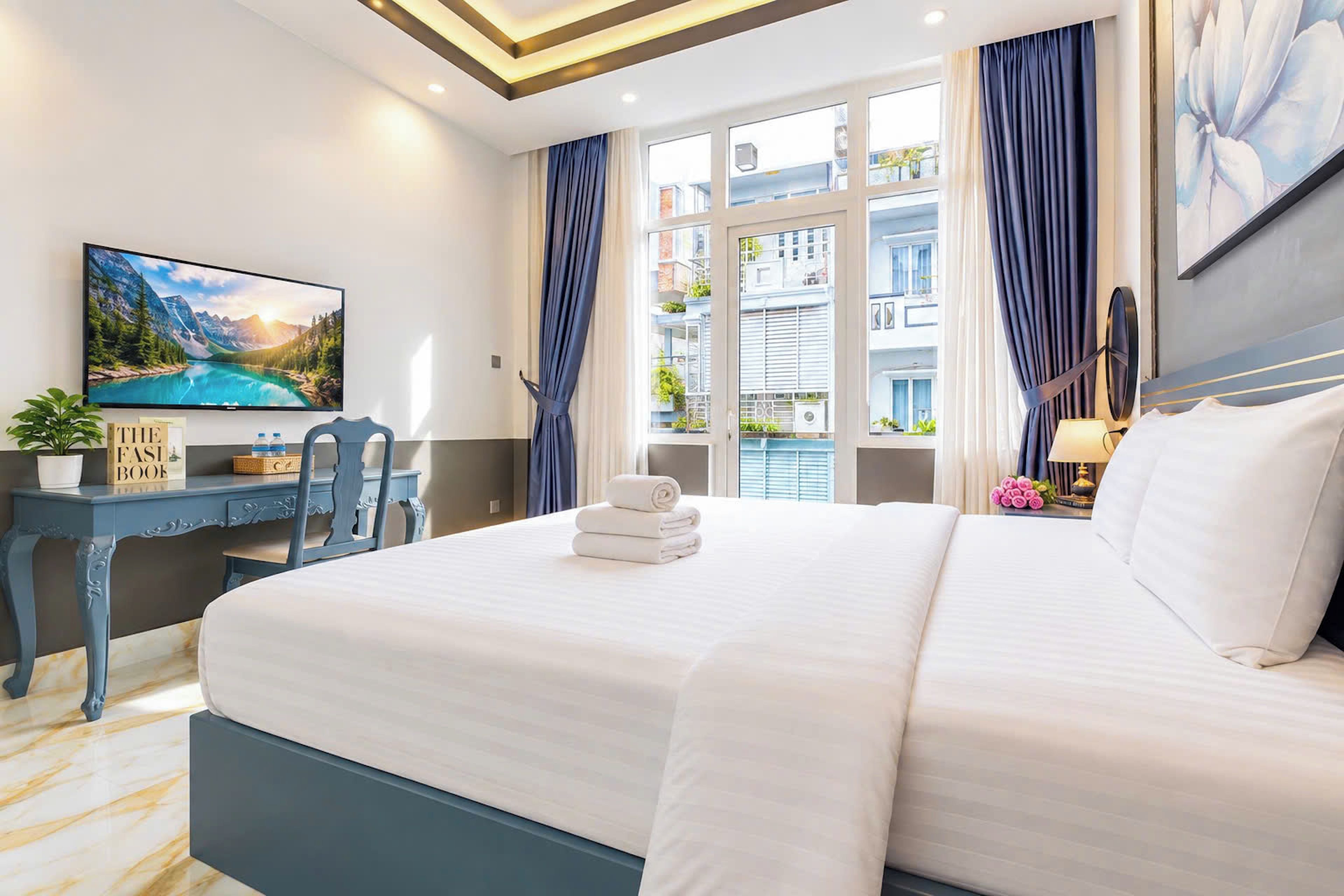 Une chambre d’hôtel avec un lit, un bureau, une chaise, une télévision et une fenêtre avec des rideaux.