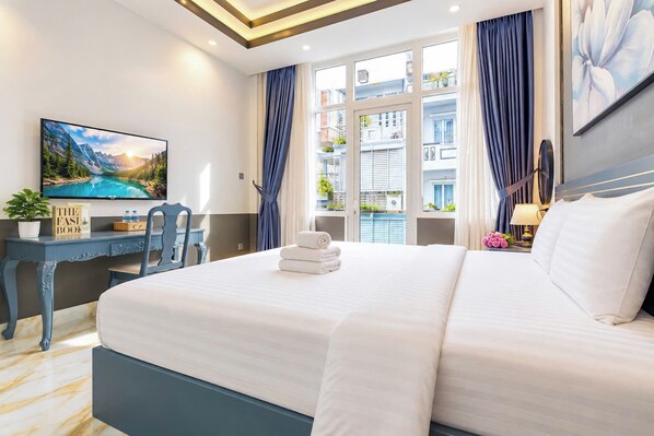 Une chambre d’hôtel avec un lit, un bureau, une chaise, une télévision et une fenêtre avec des rideaux.
