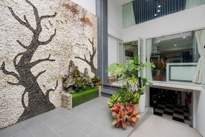 Un hall d’entrée avec un mur à motifs, un escalier et des plantes en pot.