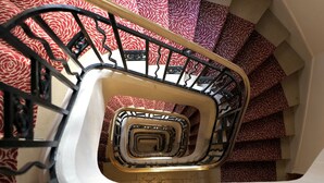 A spiral staircase with a patterned carpet. - Lovely bright and quiet 2-room apartment, Marais. 5th floor. (Paris)