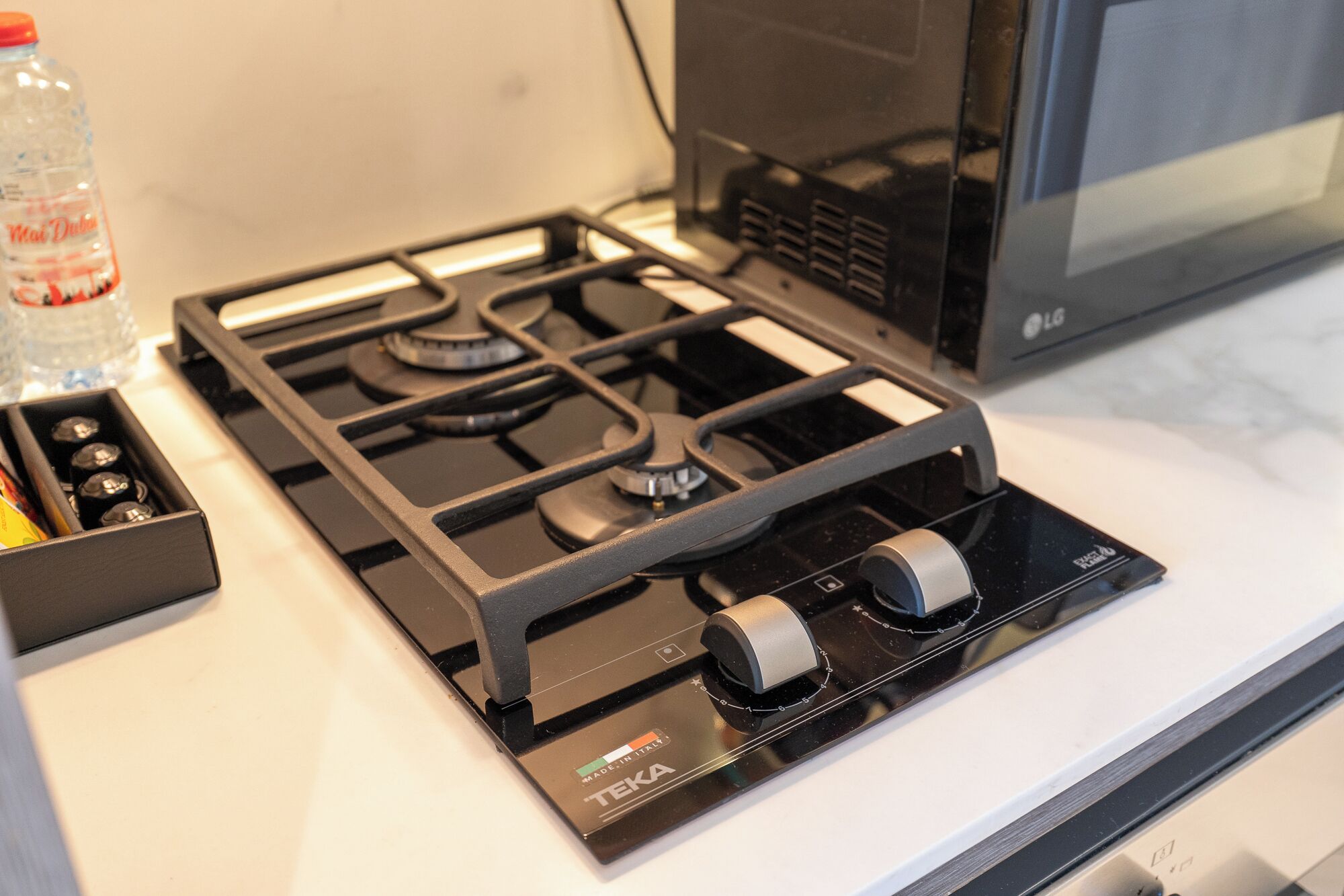 A kitchen with a black gas stove, a microwave, and a water bottle on the counter.