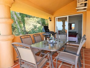 Un balcó amb taula preparada per a dos, una barbacoa i vista a l'exterior.