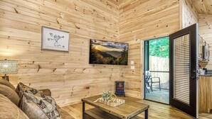 Un salón acogedor con paredes de madera, un sofá, una mesa de centro y un cuadro.