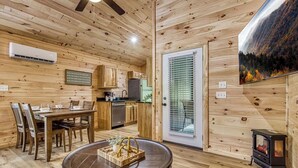 Ein Interieur einer Holzhütte mit Essbereich, Küche und Kamin.