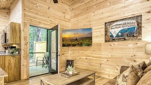 A cozy wooden cabin interior with a dining area, a sofa, and a painting of a vintage van. - Quaint Villa-Pickleball Court, Creek, WIFI, budget friendly (Cosby)