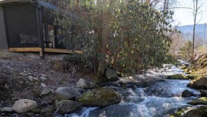Un ruisseau qui coule sur des rochers, avec une structure en bois à proximité.