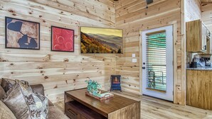 Un intérieur en bois comprenant un canapé, une table basse, un téléviseur et une porte avec des stores.