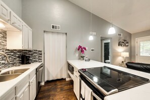 A modern kitchen with white cabinetry, a built-in microwave, and a black induction cooktop.