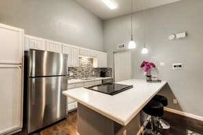 A modern kitchen with a stainless steel refrigerator, a built-in oven, and a marble countertop.